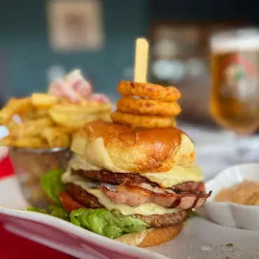 Loaded cheeseburger with onion rings, chips and a glass of beer