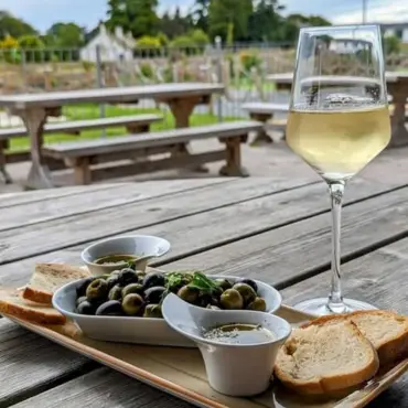 Sharing board of marinated olives and bread with a glass of white wine, on the terrace