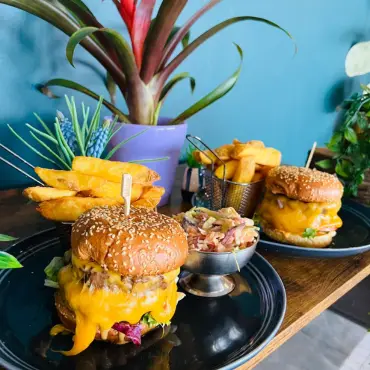 Stacked cheeseburgers with chips, served on a wooden board