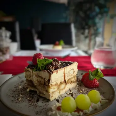 Slice of tiramisu with fresh strawberries and mint