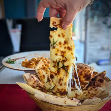 Cheesy garlic flatbread being pulled apart by hand
