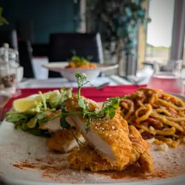 Breaded chicken escalope with pasta and dressed leaves