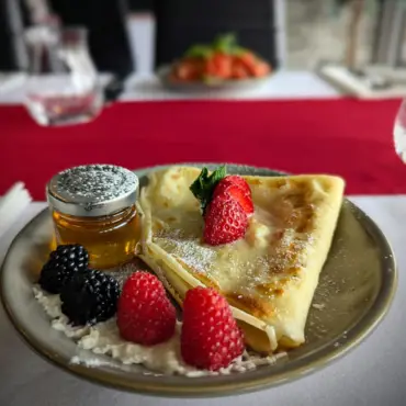 French crêpe with mixed berries, honey and icing sugar