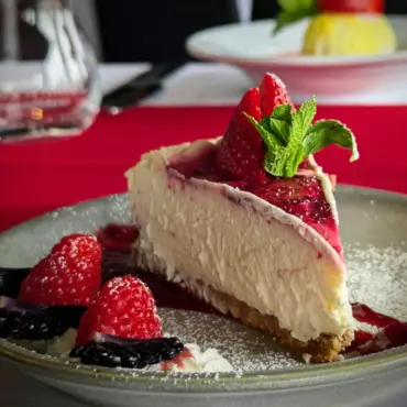 Slice of cheesecake with berry compote and fresh berries