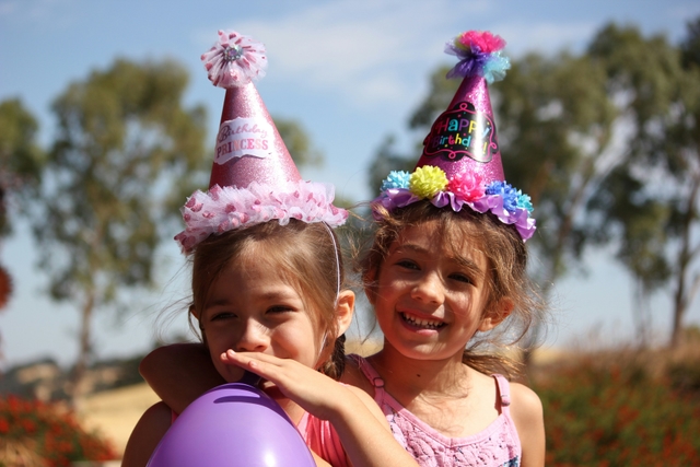 Children in party hats laughing at a birthday celebration