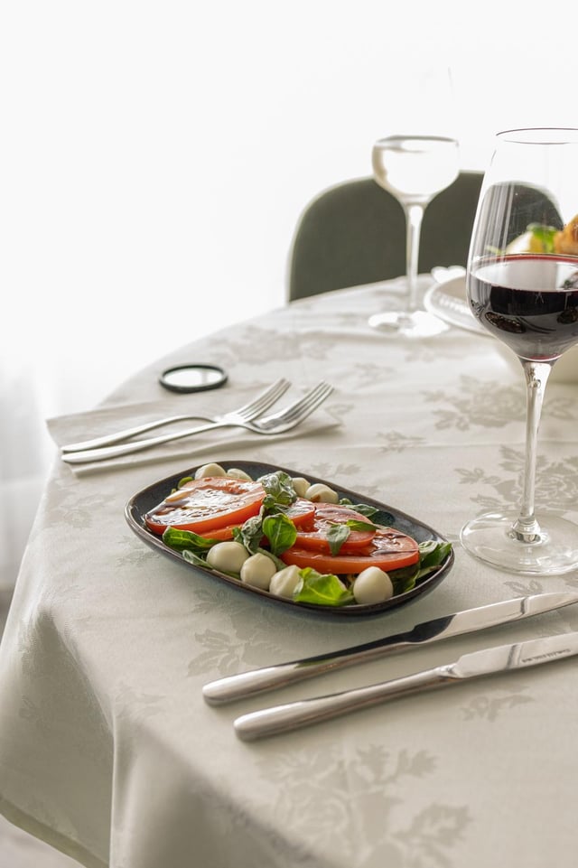 Table set with caprese salad and red wine