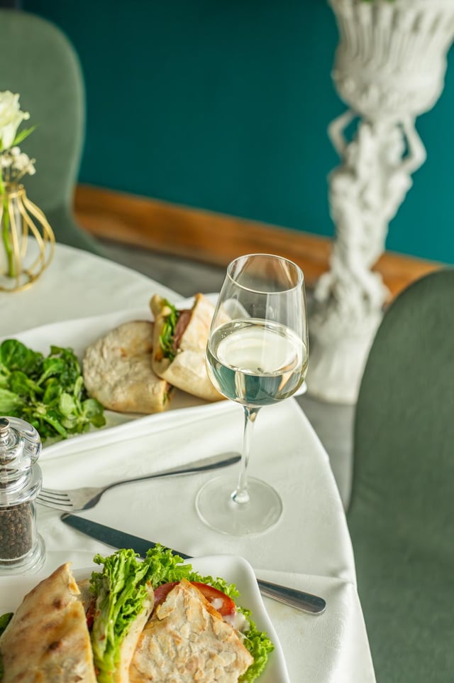 A glass of white wine beside a panini